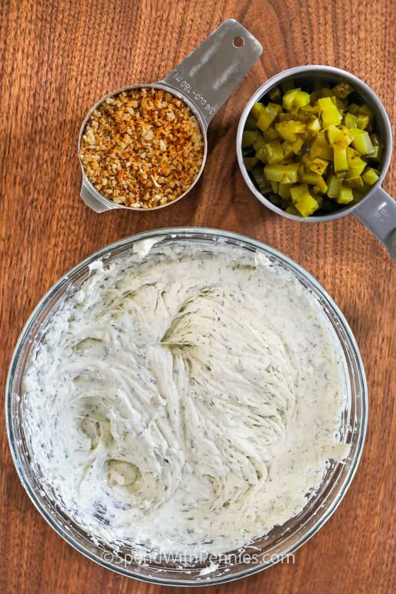 Turn those county fair crunchy deep-fried pickles into a super tasty fried pickle dip! Cream cheese, sour cream, diced pickles, savory spices, and crispy parmesan breadcrumbs make this dip extra delicious. Experiment with ranch or buffalo flavors. You probably have all the ingredients in your pantry already! It’s a true southern delight. #spendwithpennies mixed ingredients to make Fried Pickle Dip with a cup of panko breadcrumbs and pickles