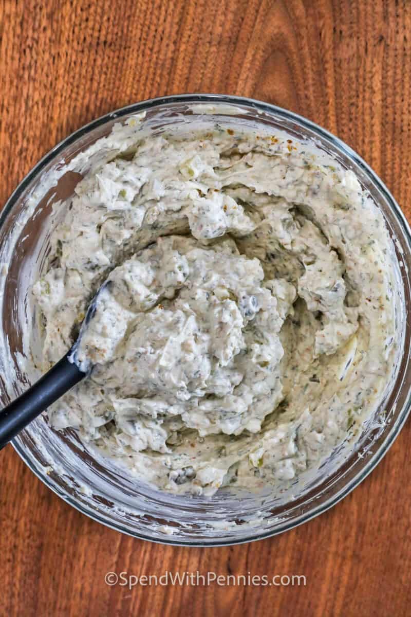 Enjoy the county fair's crunchy deep-fried pickles in a new way with this fried pickle dip! Cream cheese, sour cream, diced pickles, savory spices, and crispy parmesan breadcrumbs make it irresistible. Try adding ranch or buffalo flavors. This delicious dip is easy to make with pantry staples and brings the taste of the south to your table. #spendwithpennies Fried Pickle Dip ingredients mixed in a bowl