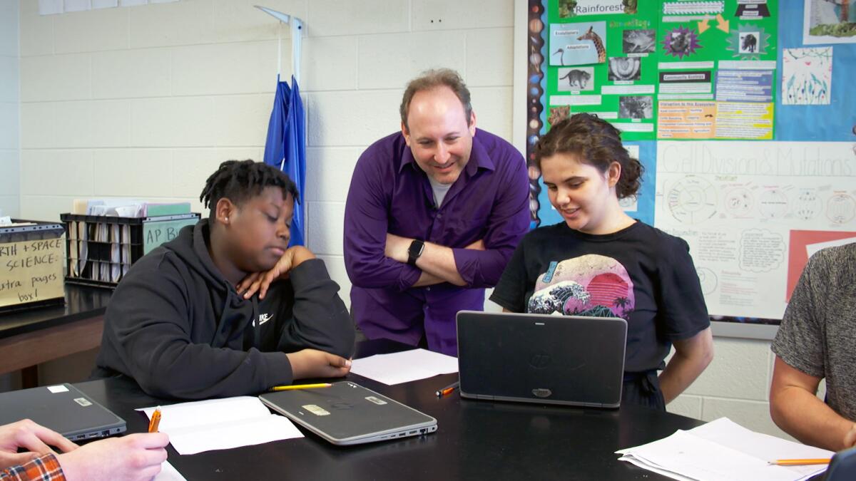 Ben Kravitz, an assistant professor of earth and atmospheric sciences at Indiana University, chats with high school students DeWayne Murphy and Emerald Yee during a class at Bloomington High School South.