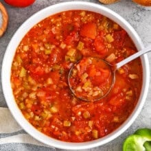 bowl of Stewed Tomatoes with vegetables and bread around it