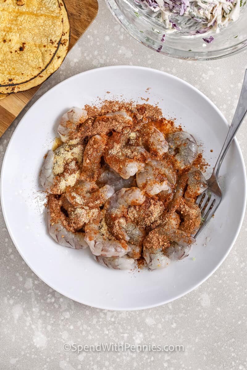 shrimp being topped with seasoning for shrimp tacos