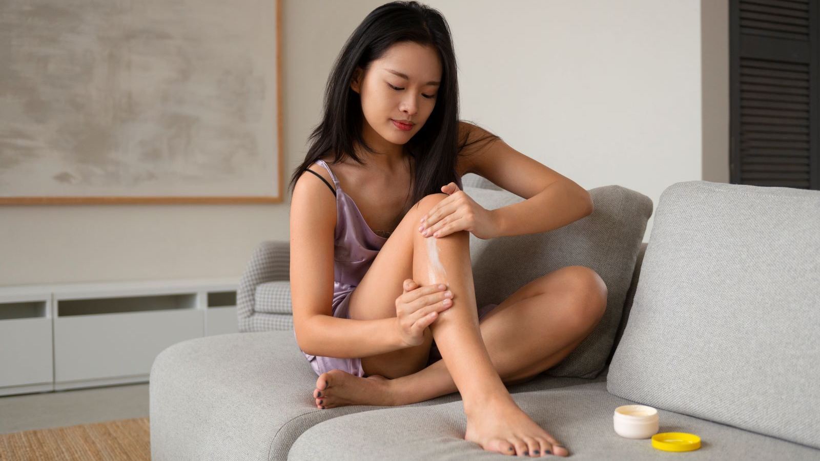 A woman applying cream on her legs