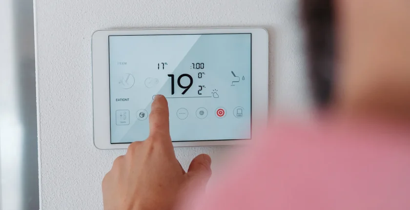 man using smart thermostat adjusting or lowering heating temperatures at.webp